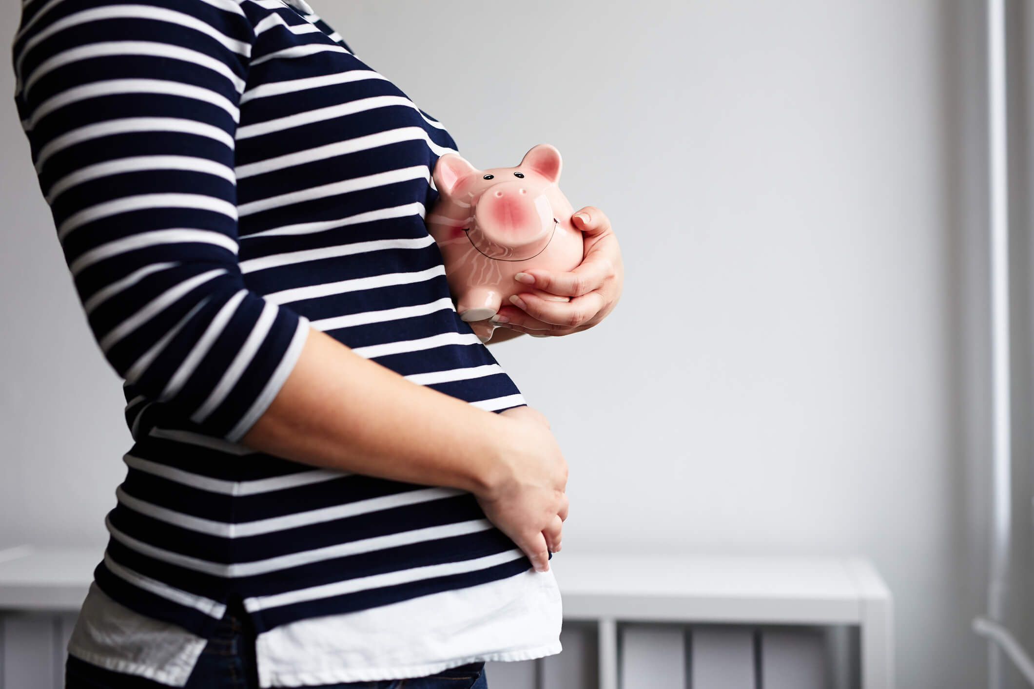 A pregnant mother holding a piggybank