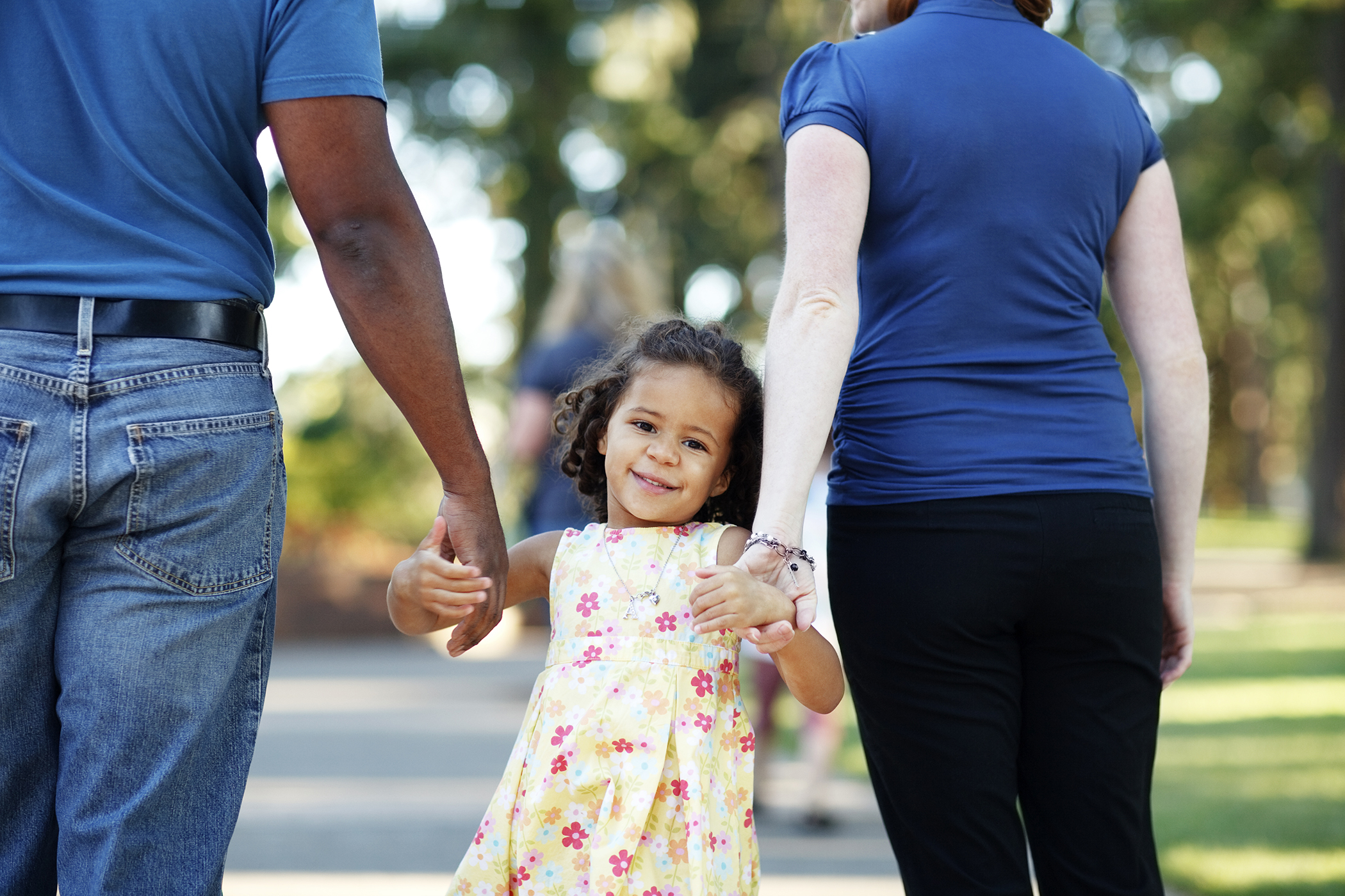 Two adults holding hands with a young girl