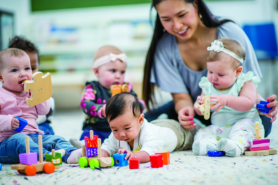 Child care provider sitting on the floor with four children 