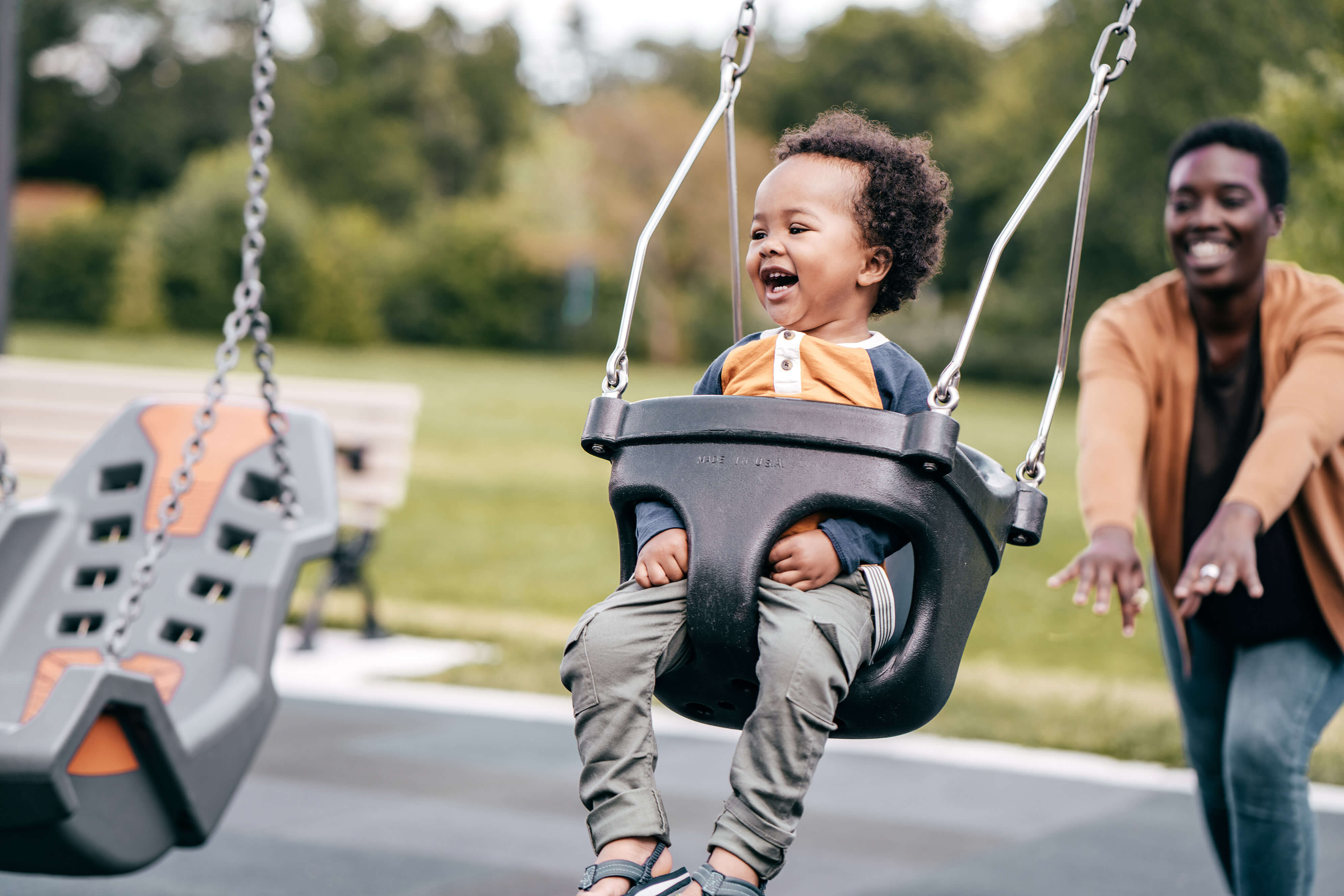 A woman pushing her child on a swing