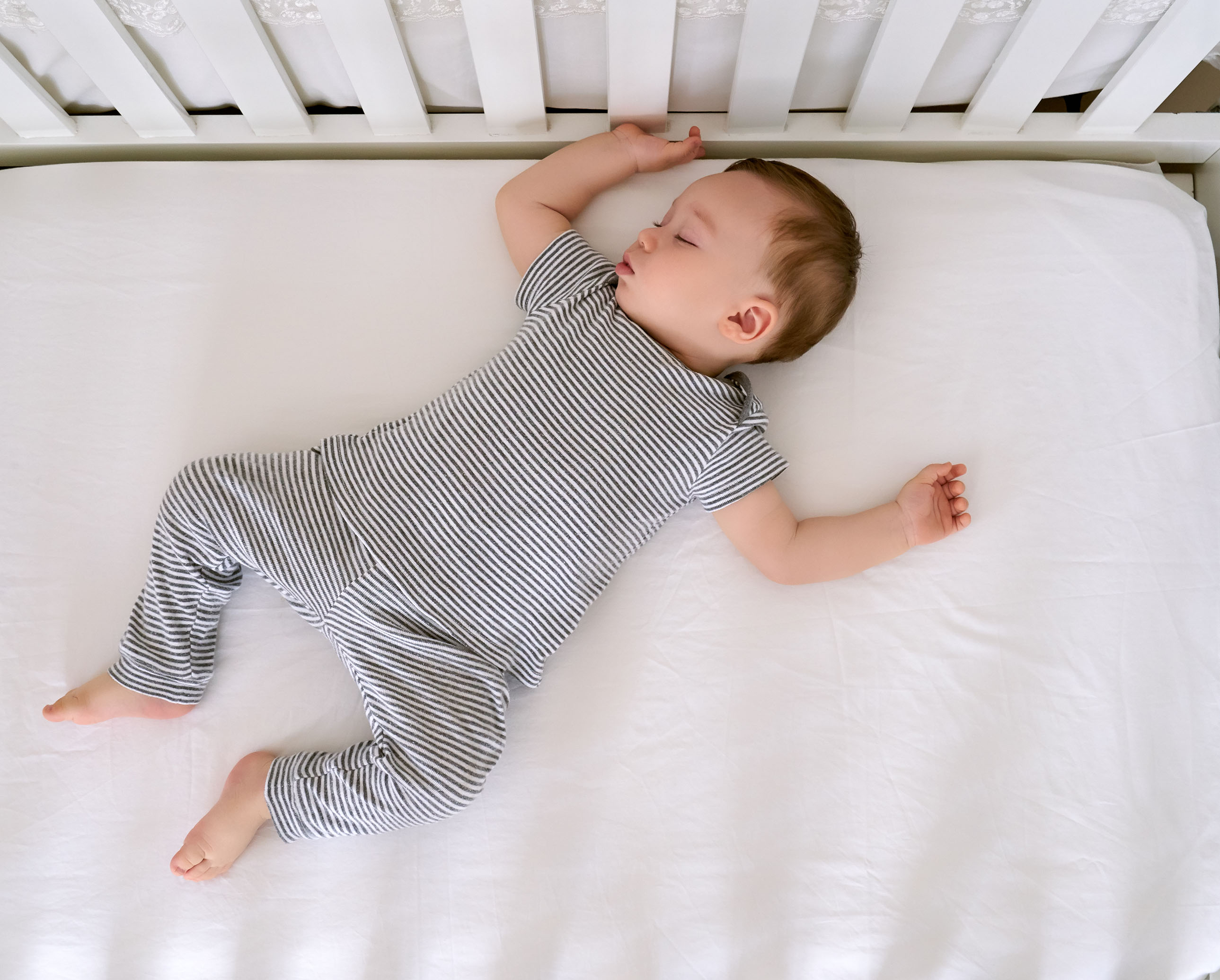 An infant sleeping on his back in a crib