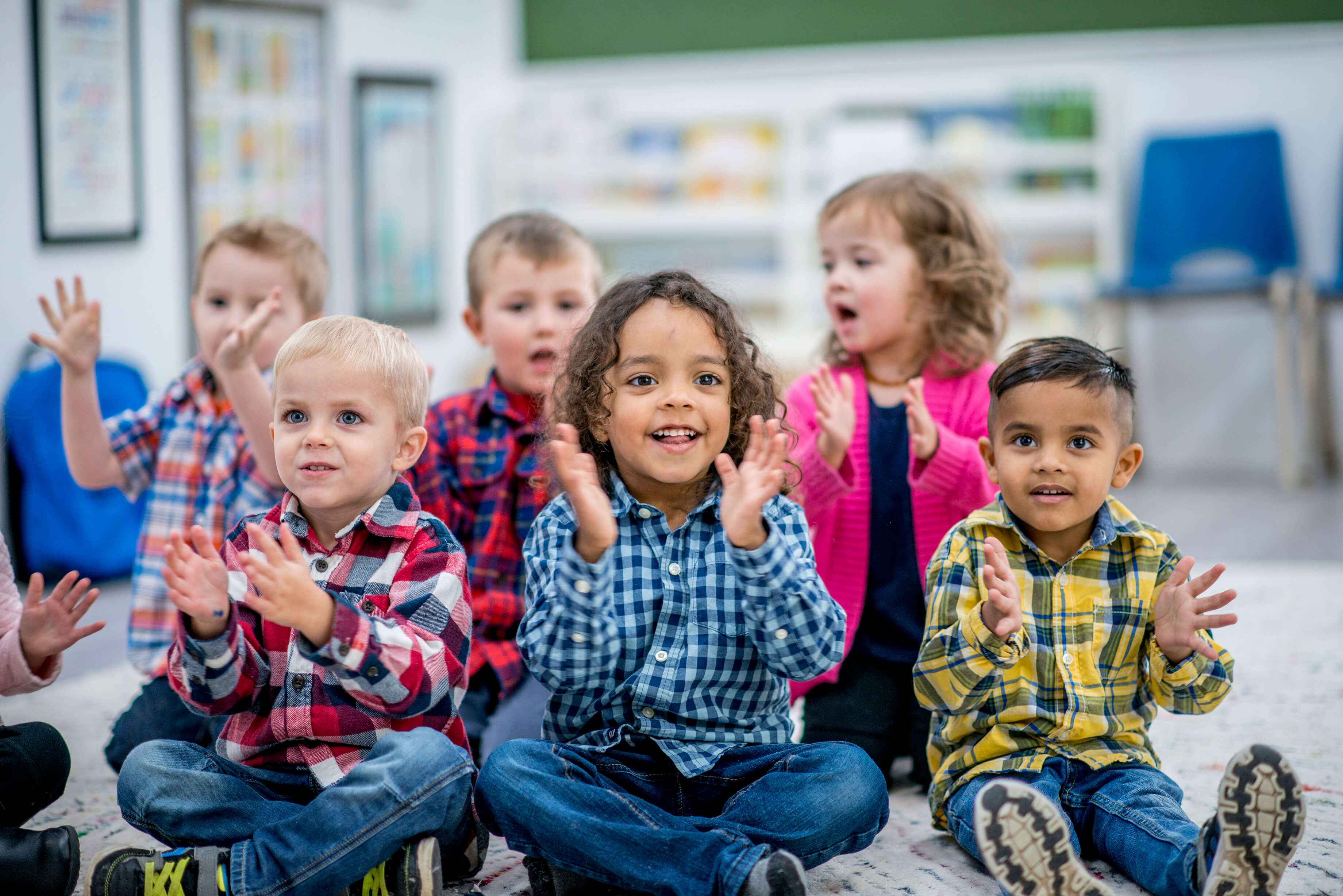 Six students sitting on the floor, clapping their hands