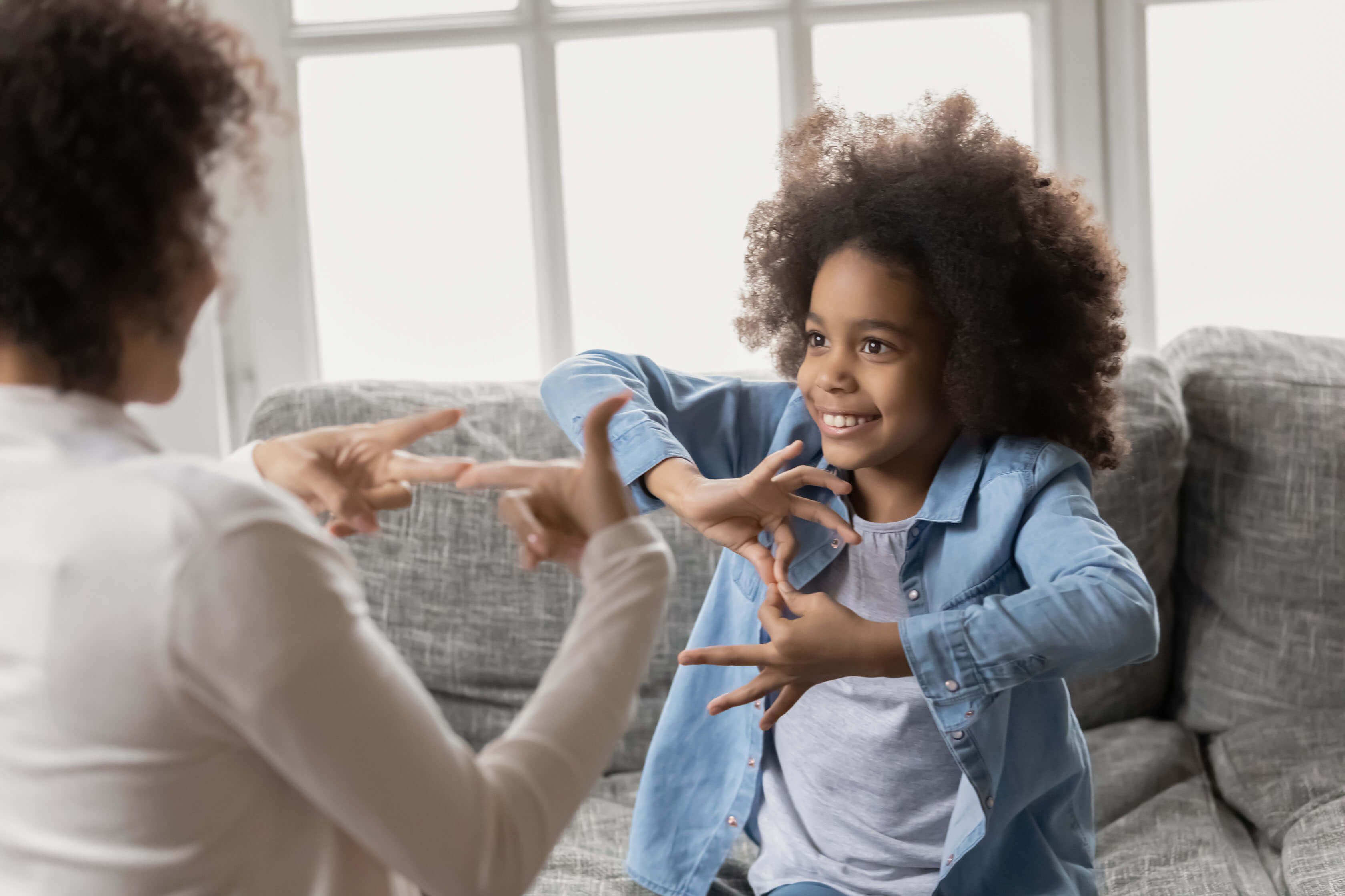 Una niña y una mujer usando lenguaje de señas.