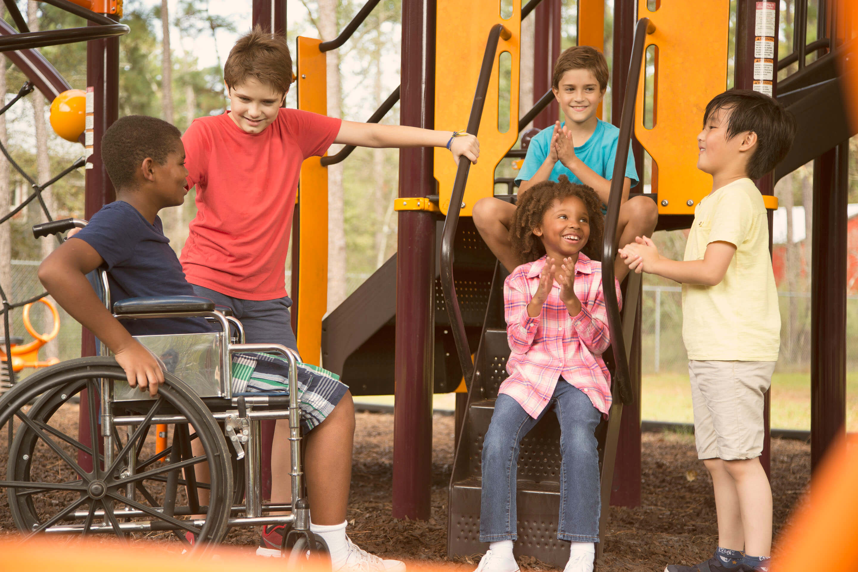 Un grupo de estudiantes, uno en silla de ruedas, jugando en el patio de recreo.