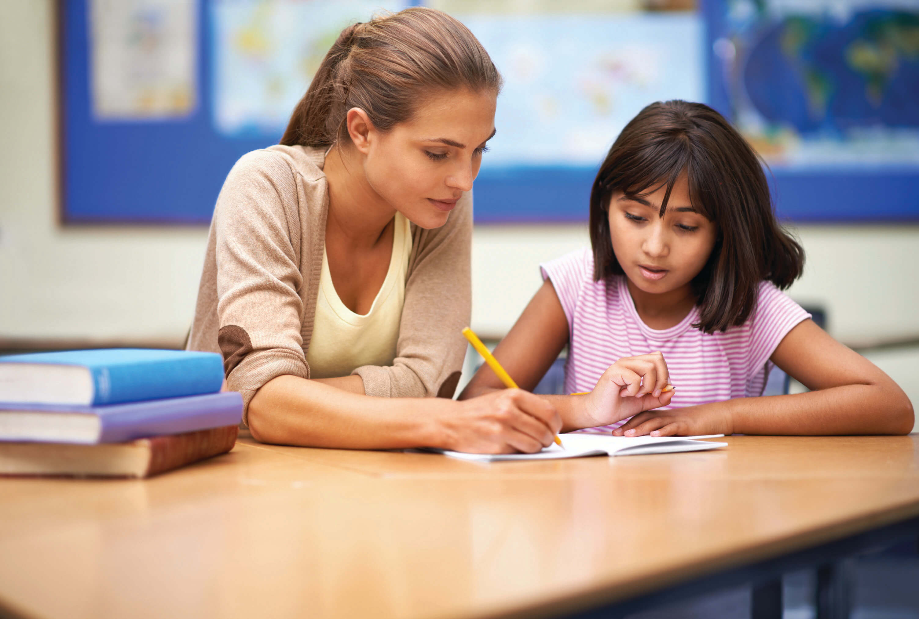 Una maestra ayudando a su alumno en su escritorio.